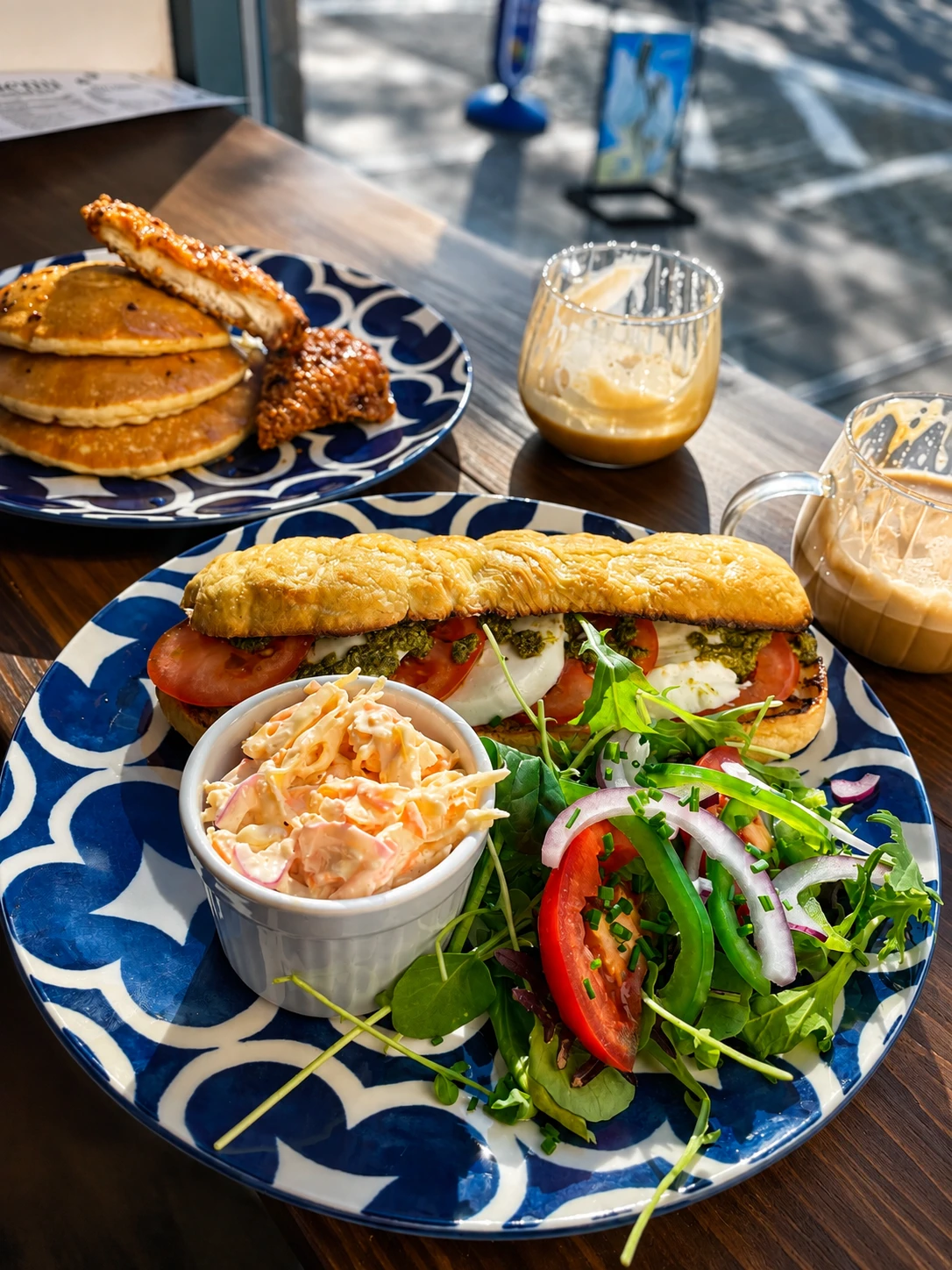 A filled sandwich with salad and coleslaw on blue patterned crockery